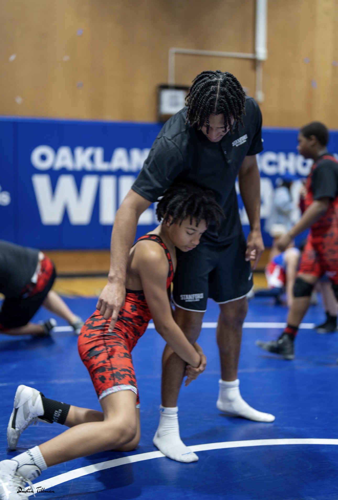 Lorenzo coaching a young wrestler at a clinic in Stanford gear